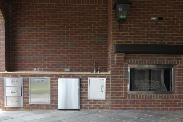 Brick outdoor kitchen with stainless steel appliances and fireplace