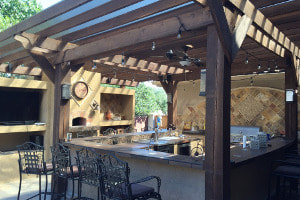 Outdoor kitchen with bar and wood pergola cover